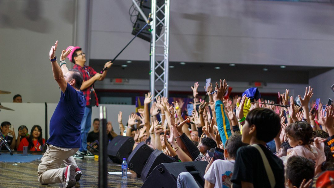 Audience members with hands raised at a live event, illustrating coordinated fan chants