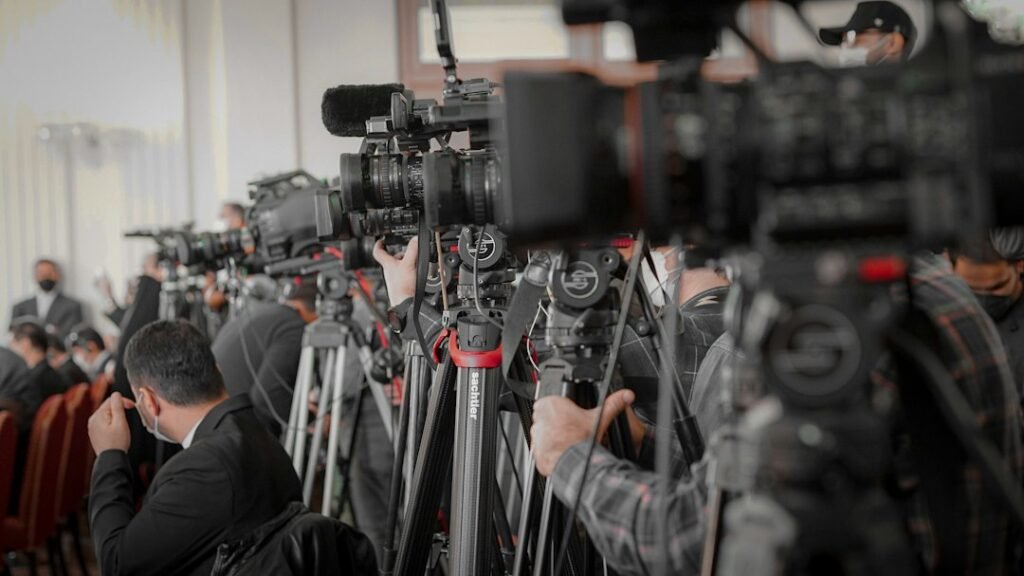 Media cameras and reporters at an event, illustrating how K-pop award stories travel through international news coverage