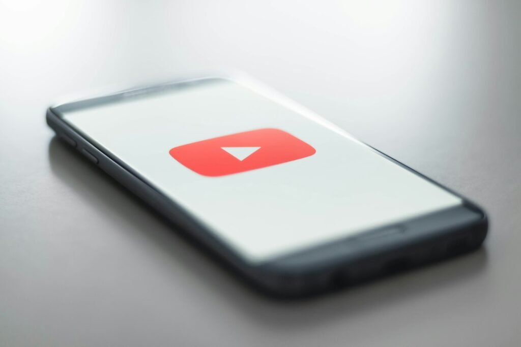 YouTube logo on a smartphone screen representing K-pop music videos reaching 100 million views